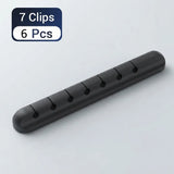 A black plastic cable clip bar shown on a light gray background, with a blue and white label in the top-left corner reading '7 Clips 6 Pcs'.
