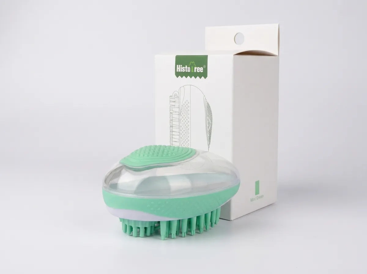 A mint green and clear silicone hair brush with green bristles, shown in front of its white packaging box with a green 'hilstar' label, on a light gray background.