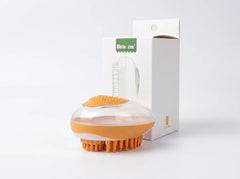 An orange and clear silicone scalp massager brush shown in front of its white product packaging box on a clean white background.