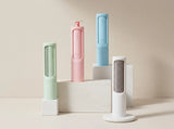 Four compact cylindrical personal care devices in pastel shades of mint green, pink, light blue, and white, arranged on white display blocks against a warm beige background.