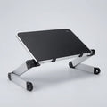 A silver aluminum laptop stand with a black top surface, shown at an angle on a light gray studio background.