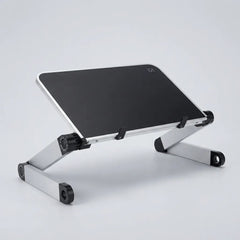 A silver aluminum laptop stand with a black top surface, shown at an angle on a light gray studio background.