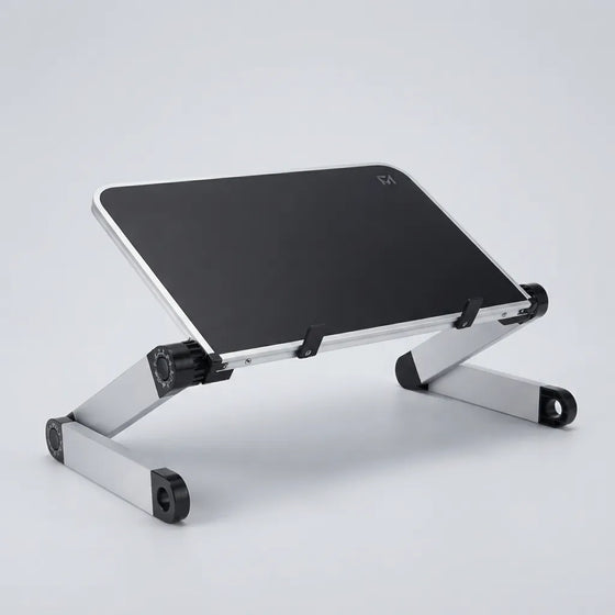 A silver aluminum laptop stand with a black top surface, shown at an angle on a light gray studio background.