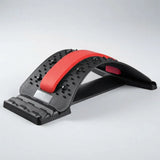 A black and red arching massage or exercise tool with textured black nubs and a red central stripe, photographed on a light gray studio background.