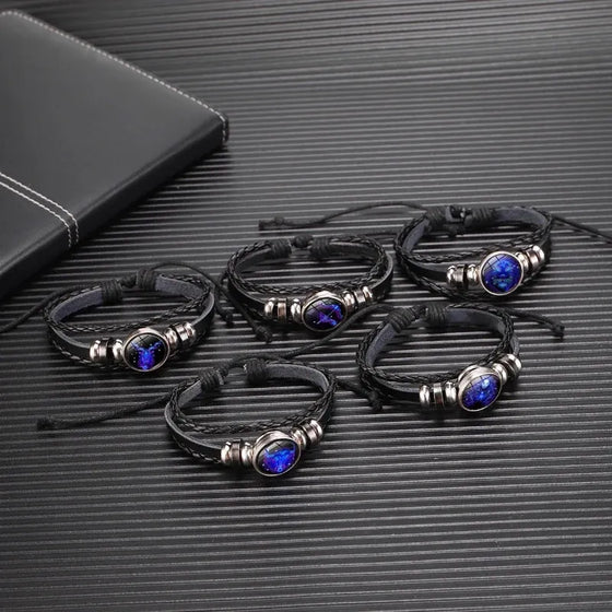 Set of black leather bracelets with blue stones on a textured surface