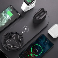 A black multi-device wireless charging pad shown with a smartphone, smartwatch, earbud charging case, and another charging phone on a dark gray surface.