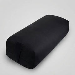 A black rectangular yoga support pillow with rounded corners, shown at an angle on a white background.