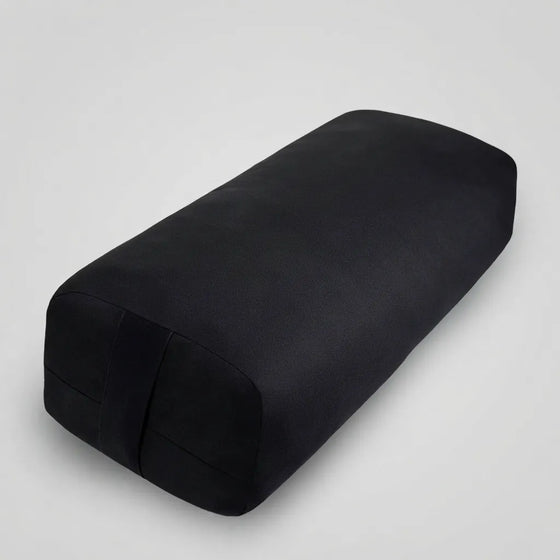 A black rectangular yoga support pillow with rounded corners, shown at an angle on a white background.