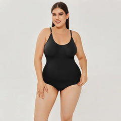 A plus-size model wearing a black one-piece bodysuit with thin shoulder straps, photographed against a plain light gray studio background.
