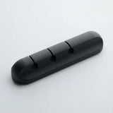 A black plastic 3-hole cable guard or cable protector with a rounded rectangular shape, shown on a light gray background.