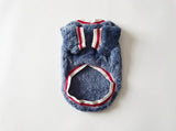 A blue fuzzy pet sweater or vest with red and white striped trim, laid flat on a white background.
