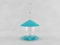A bird feeder with a bright turquoise blue conical lid, a clear plastic cup in the center, and a matching turquoise base, suspended by a thin metal wire loop against a light gray background.