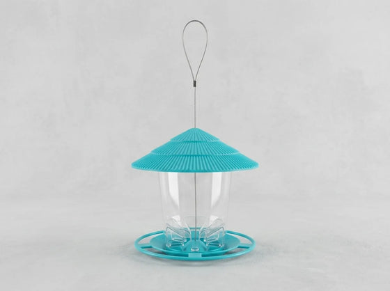 A bird feeder with a bright turquoise blue conical lid, a clear plastic cup in the center, and a matching turquoise base, suspended by a thin metal wire loop against a light gray background.