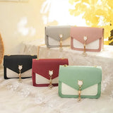 Five colorful handbags with cat-shaped charms on a soft surface.