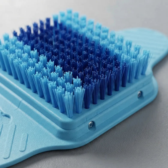 A close-up of a blue foot massager brush with dense bristles transitioning from light blue to dark navy, set against a neutral gray background.