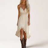 A woman modeling a cream-colored crochet halter midi dress with a high-low hem and brown cowboy boots, set against a plain off-white studio background.