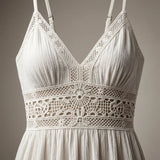 A close-up of a white crochet lace halter top with a textured crinkled fabric, featuring a wide decorative lace band at the waist and thin shoulder straps.