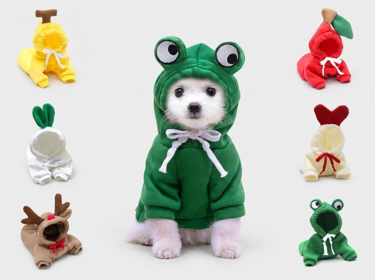 A small white dog wearing a green frog costume hoodie, centered on a light gray background, with six other plush pet costume options shown around it.