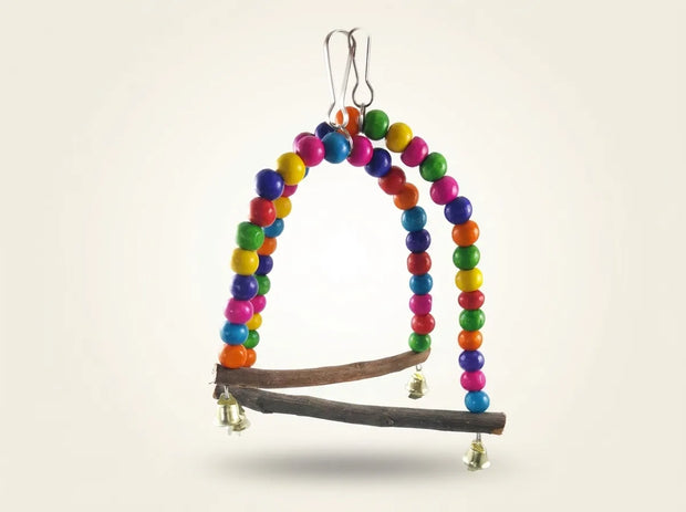 A hanging bird toy made from a natural twig branch with two arched loops of colorful wooden beads in red, orange, yellow, green, blue, and purple, plus small hanging bells.