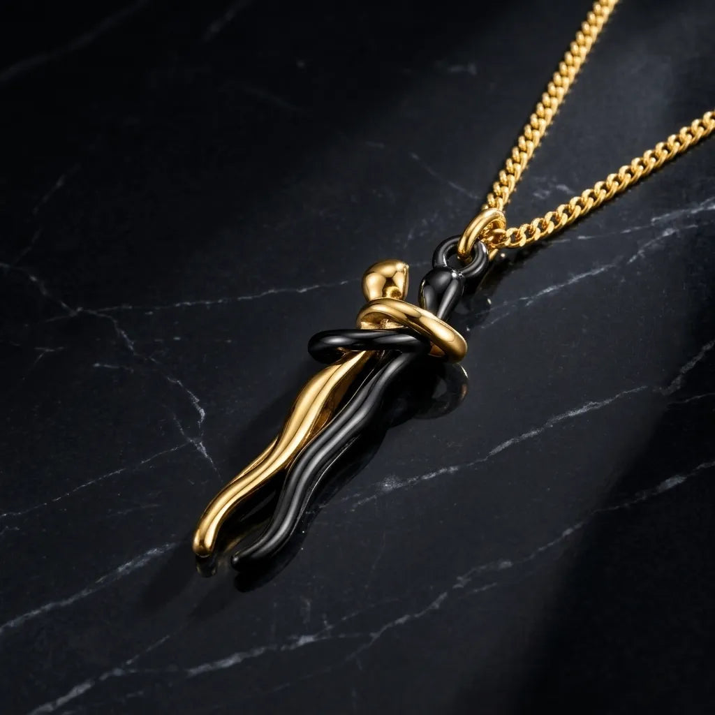 A gold chain necklace with a pendant featuring a black and gold abstract, wavy design, displayed on a dark marble surface.