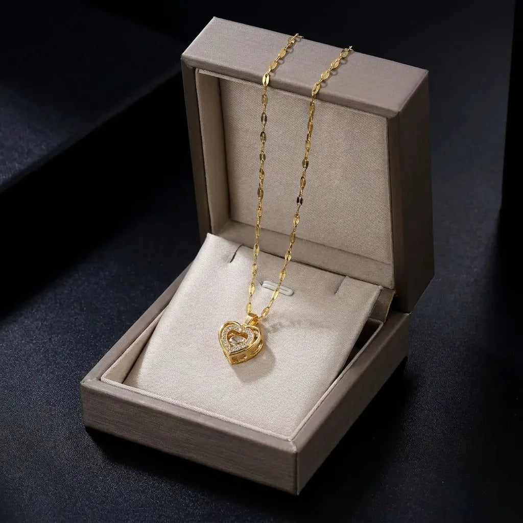 A gold heart-shaped pendant necklace displayed inside an open beige jewelry box on a dark background.