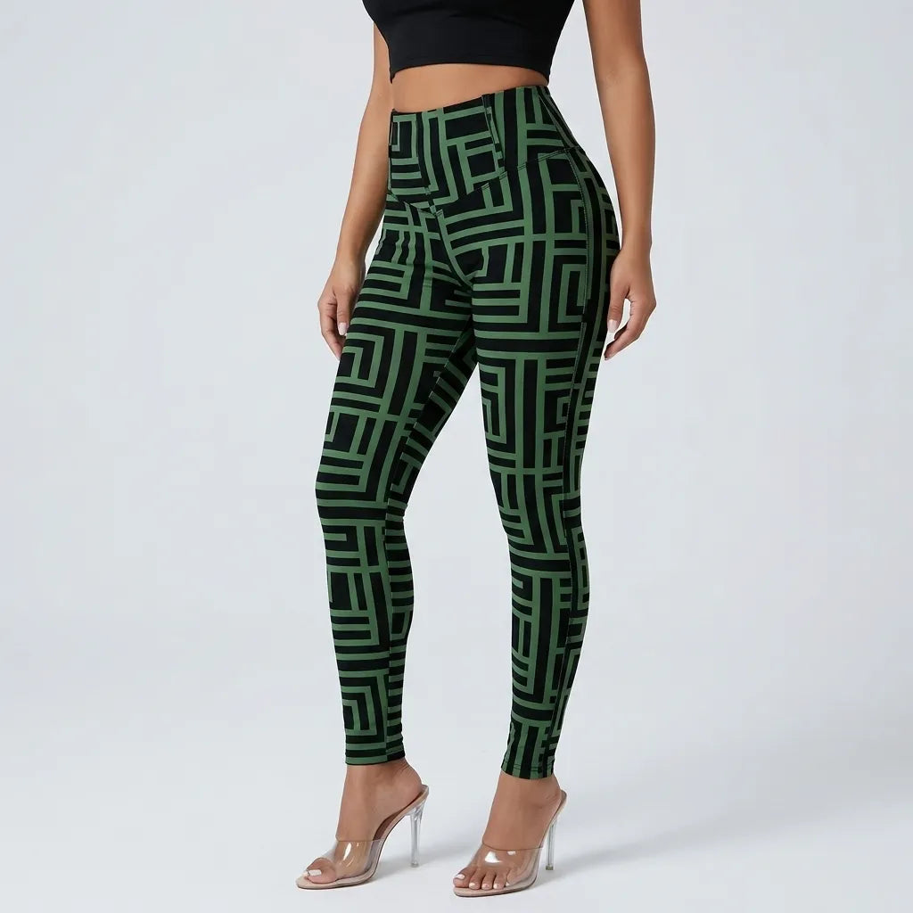 A model wearing high-waisted leggings with a green and black geometric maze-like pattern, paired with clear high-heeled sandals against a light gray studio background.