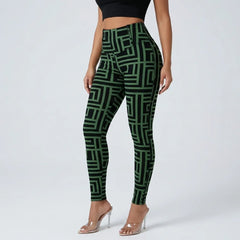A model wearing high-waisted leggings with a green and black geometric maze-like pattern, paired with clear high-heeled sandals against a light gray studio background.