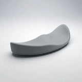 A modern, curved gray ergonomic chair cushion or seat pad, photographed on a clean light gray studio background.