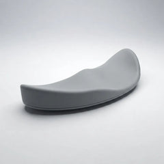 A modern, curved gray ergonomic chair cushion or seat pad, photographed on a clean light gray studio background.