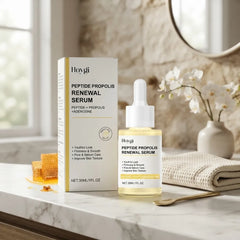 Hoygi Peptide Propolis Renewal Serum shown with its product box and dropper bottle on a marble countertop, styled with a honeycomb, folded towel, flowers, and a mirror in a bright bathroom setting.