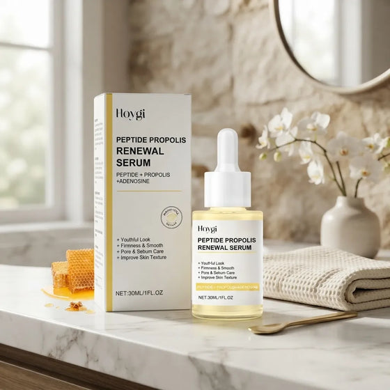 Hoygi Peptide Propolis Renewal Serum shown with its product box and dropper bottle on a marble countertop, styled with a honeycomb, folded towel, flowers, and a mirror in a bright bathroom setting.