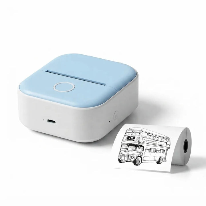 A compact square printer or label maker in light blue and white, shown with a short roll of white paper printed with a black-and-white double-decker bus illustration on a clean white background.