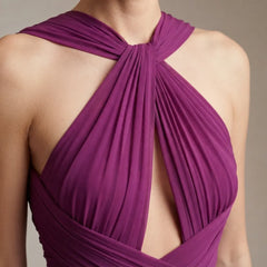 Close-up of a model wearing a draped halter-style top in a rich magenta-purple fabric, showing the intricate crisscross back design and wrap-around front details.