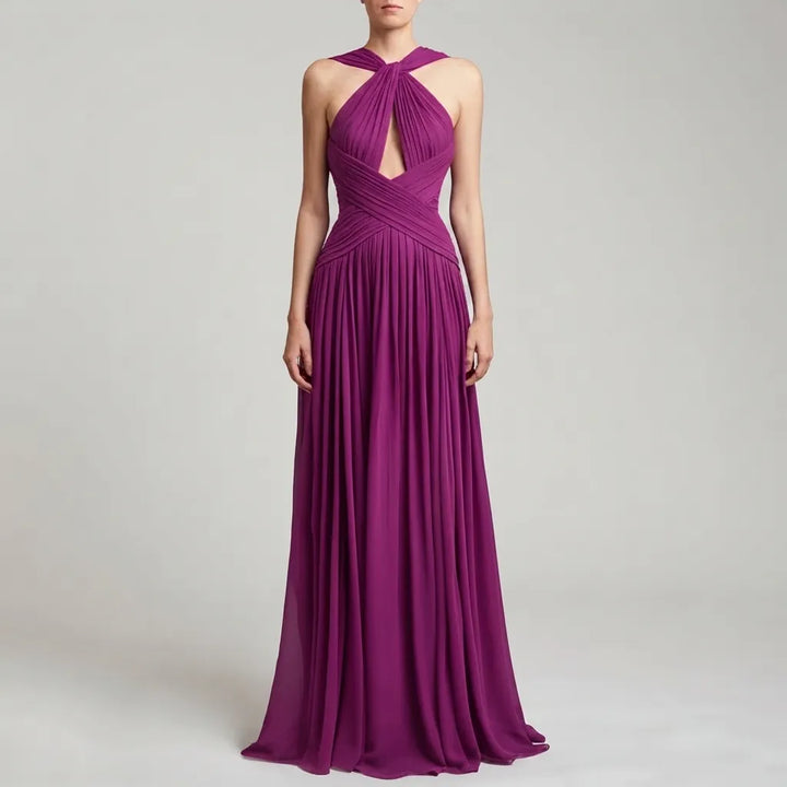 A woman modeling a floor-length magenta purple halter gown with a keyhole cutout at the bust and a pleated draped bodice, set against a light gray studio background.