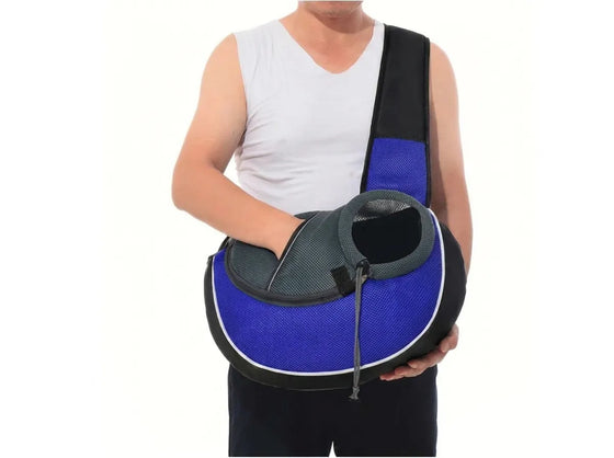 A person wearing a white sleeveless shirt holds a blue and black pet carrier bag against their chest. The bag has a blue mesh body, black trim, and a black shoulder strap, shown against a plain white background.
