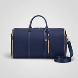 A navy blue leather duffel bag with gold-tone hardware, featuring dual top handles, a detachable shoulder strap, and a tassel zipper pull, shown on a light gray background.