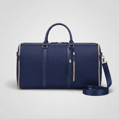 A navy blue leather duffel bag with gold-tone hardware, featuring dual top handles, a detachable shoulder strap, and a tassel zipper pull, shown on a light gray background.