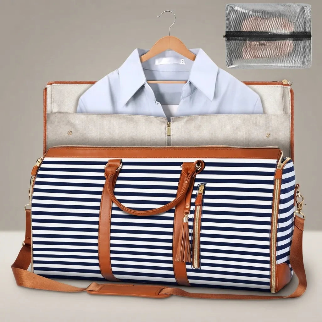 A striped duffel bag with tan leather handles and trim, shown with a light blue dress shirt inside a larger garment bag and a small clear pouch in the upper right. The main bag has navy and white horizontal stripes with gold-tone hardware.