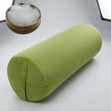 An olive green cylindrical bolster pillow shown on a light gray studio background, with a small inset of white filling material in a wooden bowl.