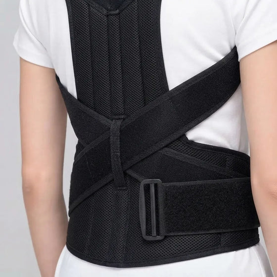 A black posture corrector back brace worn by a person, shown from the back over a white t-shirt. The brace features a breathable mesh back panel and adjustable straps with a plastic buckle.