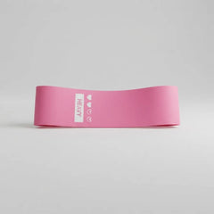 A pink resistance band with a white vertical label reading 'HEAVY' and small heart icons, photographed on a clean light gray studio background.