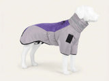 A dog coat shown on a white dog mannequin against a light beige studio background. The coat is light gray with a purple panel on the back and a black rectangular patch on the side.