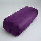 A purple cylindrical yoga bolster pillow with a textured fabric surface, shown on a neutral light gray background.