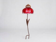 A metal flower garden stake sculpture with a vibrant red petal-shaped top, a brown mesh center, and a long brown stem with leaves, standing on a white studio background.