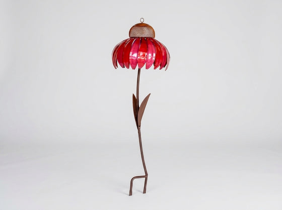 A metal flower garden stake sculpture with a vibrant red petal-shaped top, a brown mesh center, and a long brown stem with leaves, standing on a white studio background.