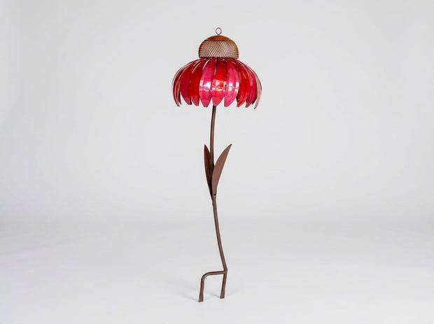 A metal flower garden stake sculpture with a vibrant red petal-shaped top, a brown mesh center, and a long brown stem with leaves, standing on a white studio background.