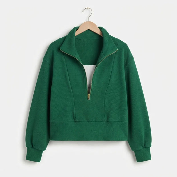 A green ribbed knit half-zip sweatshirt with a stand collar, displayed on a wooden hanger against a light gray background.