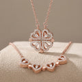 Rose gold jewelry set featuring a four-leaf clover pendant necklace and a matching heart-link bracelet, both adorned with clear rhinestones, displayed on a textured beige surface.