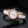 A women's quartz watch with a rose gold metal bracelet, white ceramic links, and a white mother-of-pearl dial accented with rhinestones.