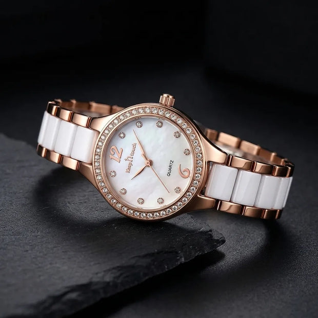 A women's quartz watch with a rose gold metal bracelet, white ceramic links, and a white mother-of-pearl dial accented with rhinestones.